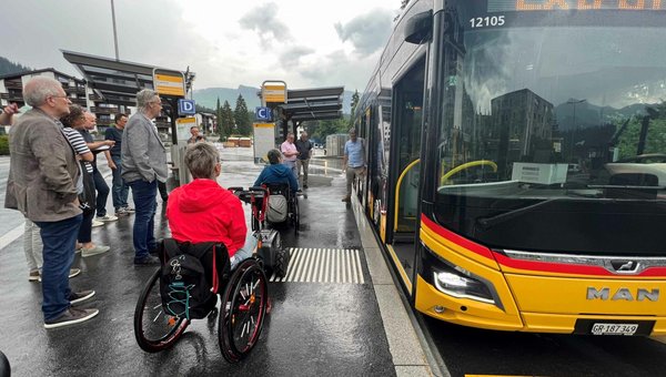 Menschen mit und ohne Rollstuhl steigen in ein Postauto ein