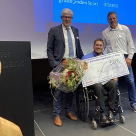 Jonas Frei hält den Check von Fr. 5000.-, flankiert von Beat Hefti und Regierungsrat Parolini